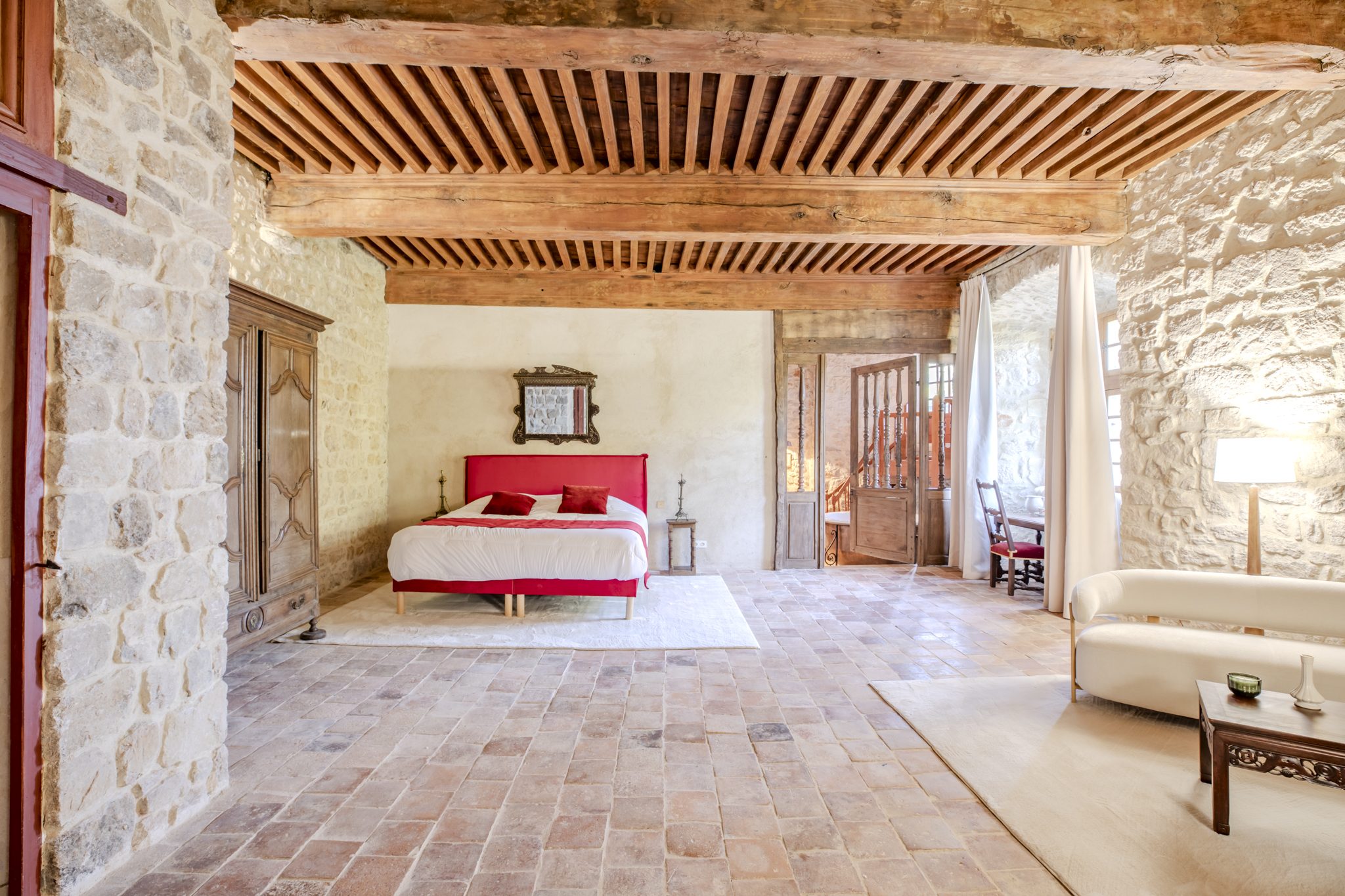 Grande chambre au lit rouge, sous un plafond à la française