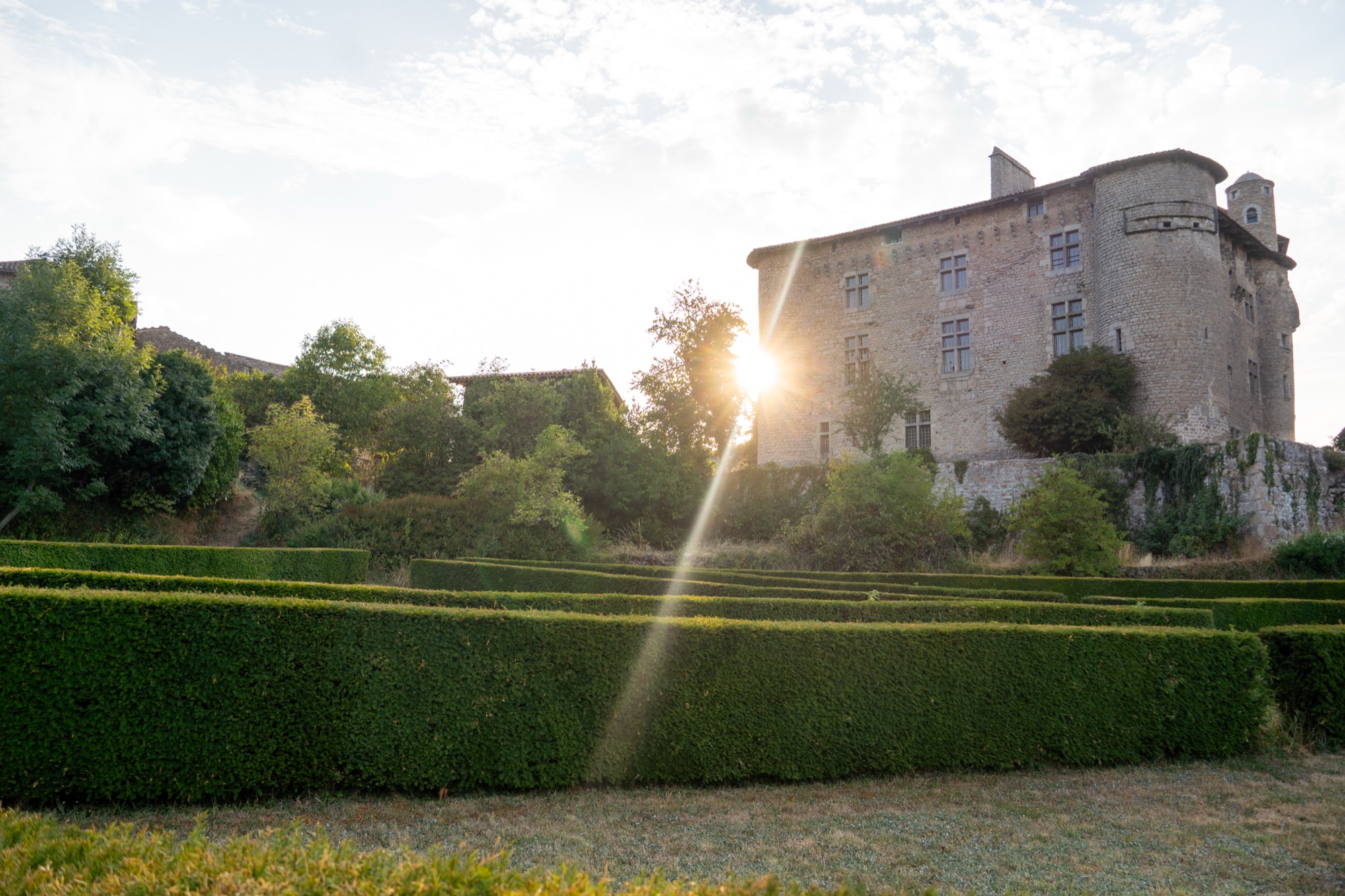 Le soleil couchant derrière le château et ses jardins taillés